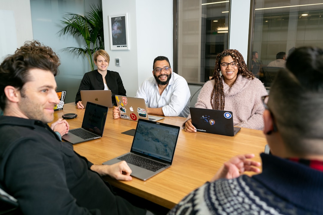 Team on laptops in board meeting representing agency client site management