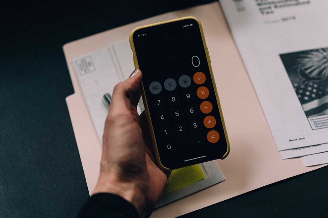 Hand holding smartphone with calculator app for budgeting hosting costs